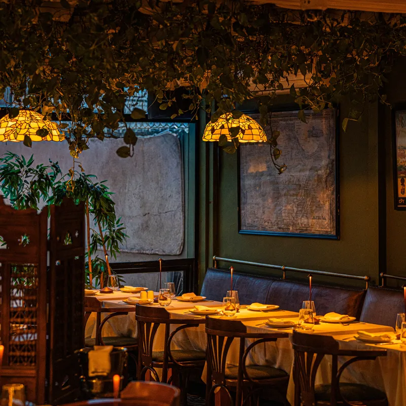 Warm verlicht interieur van restaurant San Thomas met houten tafels en sfeervolle verlichting